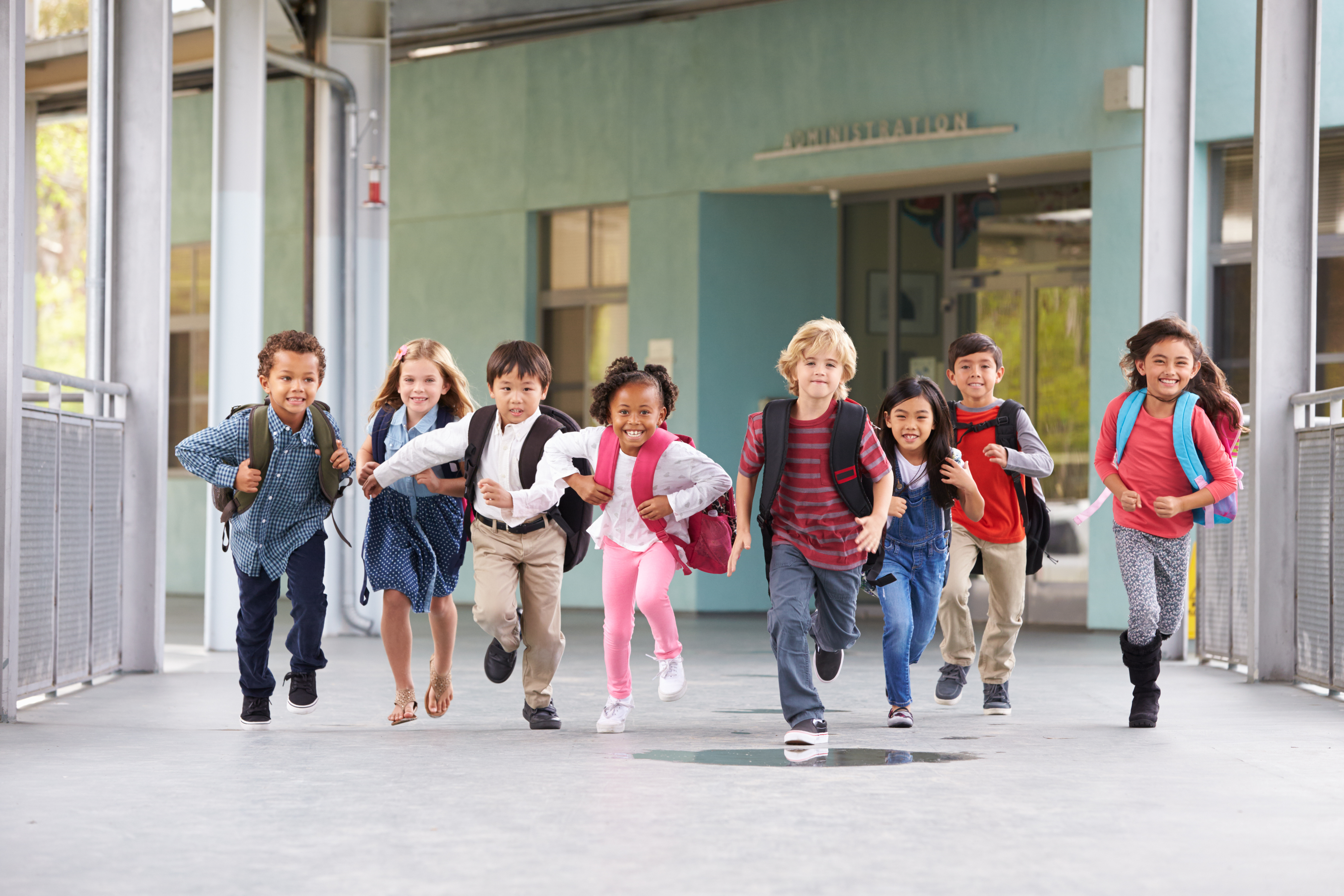 Kids with backpacks running in school